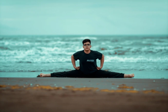 a man sitting in a yoga pose on the beach